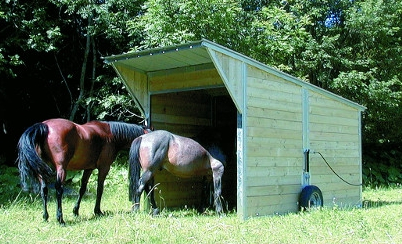 Cet abri mobile de Base avec deux chevaux est dans la pâture. C'est un abri déplaçable grâce à ses deux roues pour suivre les chevaux dans les différentes prairies.